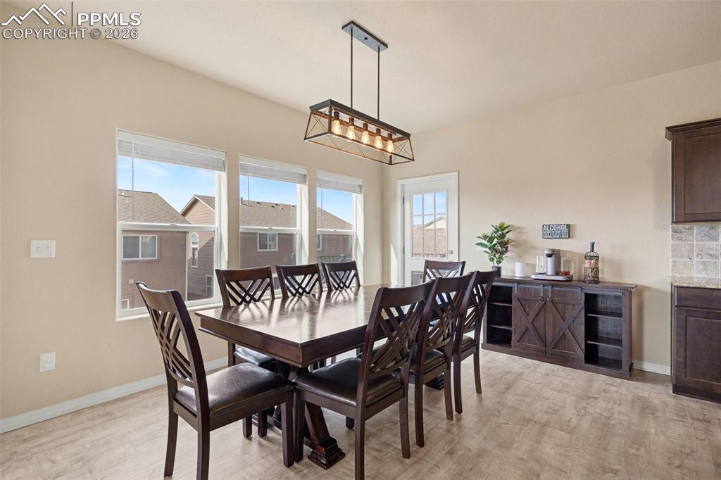 Image 7 of 40: Dining area featuring a linear chandelier, triple windows, and wood-finish 