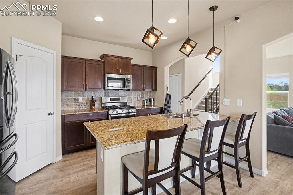 Image 8 of 40: Kitchen featuring rich wood cabinetry, stainless steel appliances, a tile b