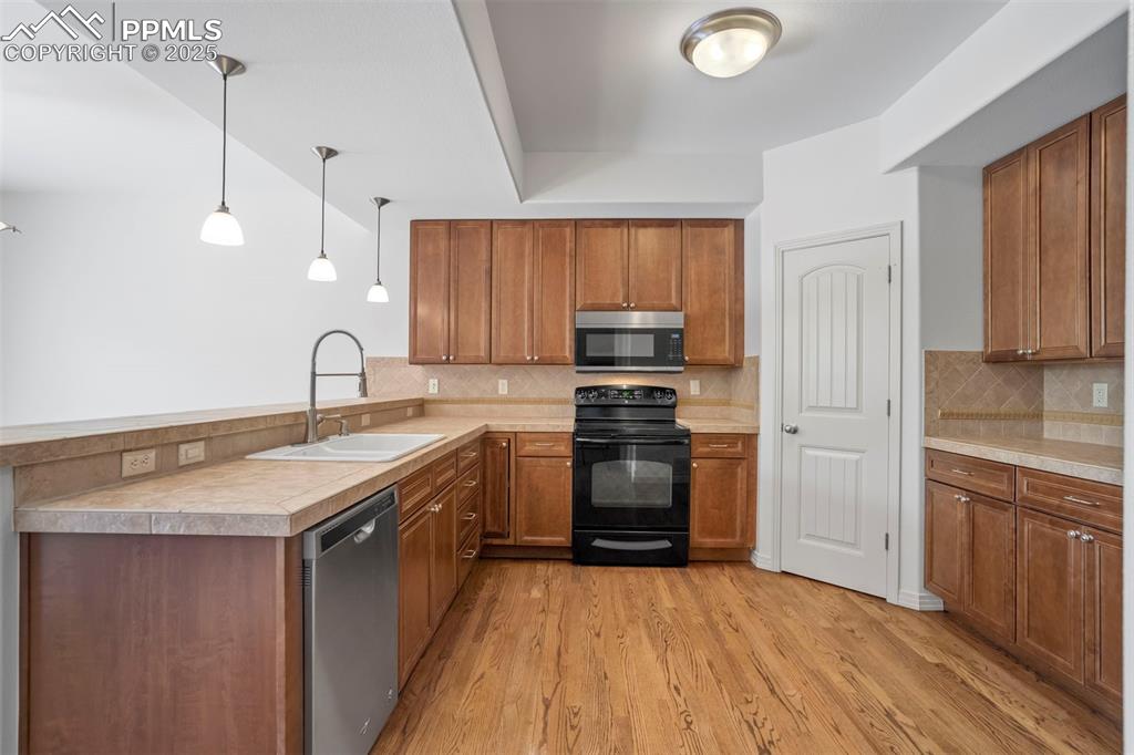Image 11 of 50: Kitchen with appliances with stainless steel finishes, decorative backsplas