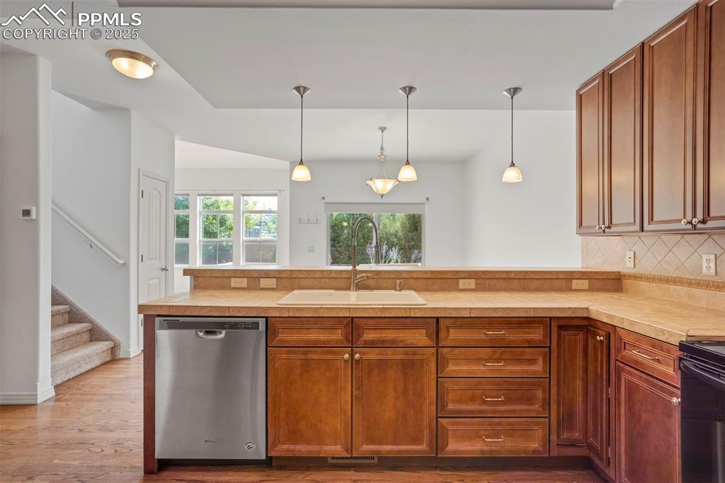 Image 12 of 50: Kitchen with stainless steel dishwasher, a peninsula, wood finished floors,