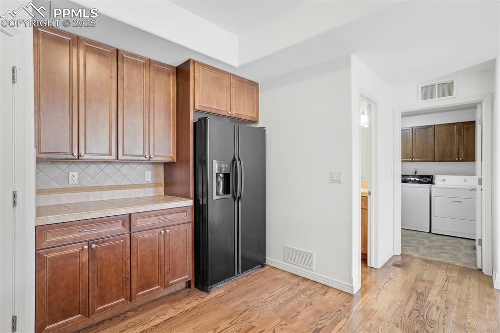 Image 13 of 50: Kitchen with washing machine and clothes dryer, black fridge with ice dispe