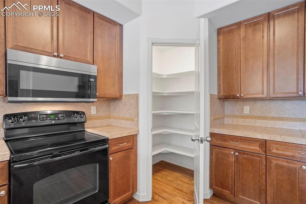Image 14 of 50: Kitchen featuring black range with electric cooktop, stainless steel microw