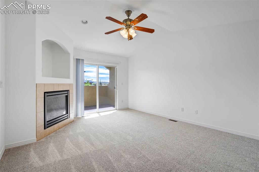 Image 17 of 50: Bedroom featuring access to exterior, light colored carpet, a tiled firepla