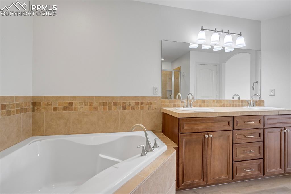 Image 21 of 50: Full bath with double vanity, a bath, and a shower stall