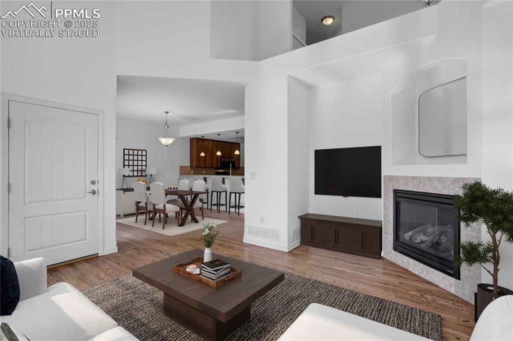 Image 3 of 50: Living room with a high ceiling, wood finished floors, and a glass covered