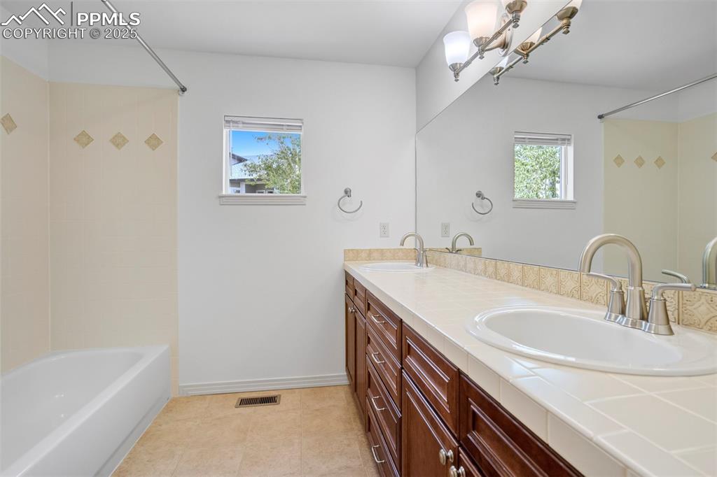 Image 31 of 50: Full bath featuring double vanity and bathtub / shower combination