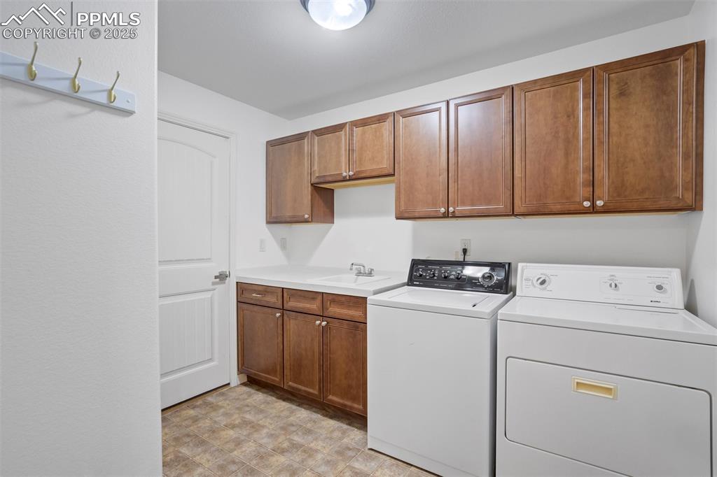 Image 34 of 50: Washroom featuring washer and dryer and cabinet space
