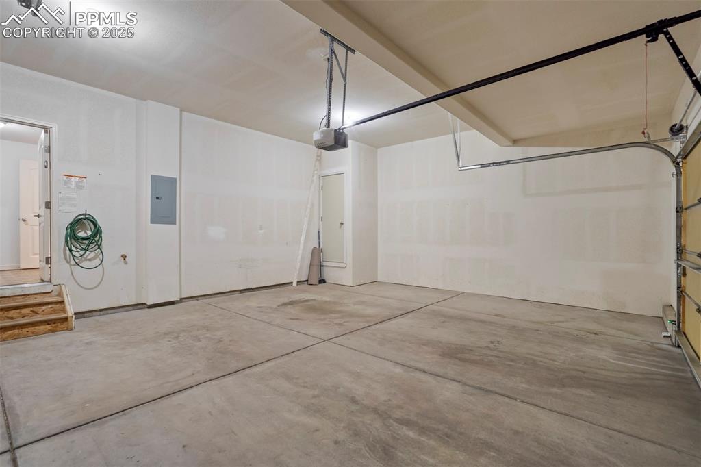 Image 37 of 50: Garage featuring electric panel and a garage door opener