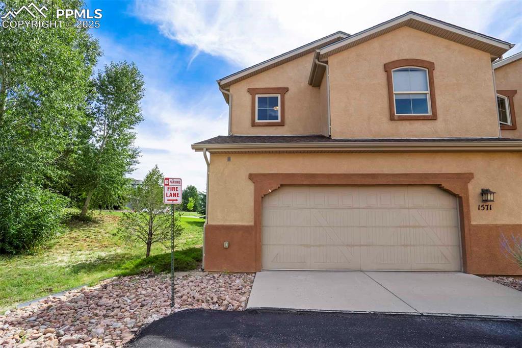 Image 38 of 50: View of front of home featuring stucco siding, a garage, and concrete drive