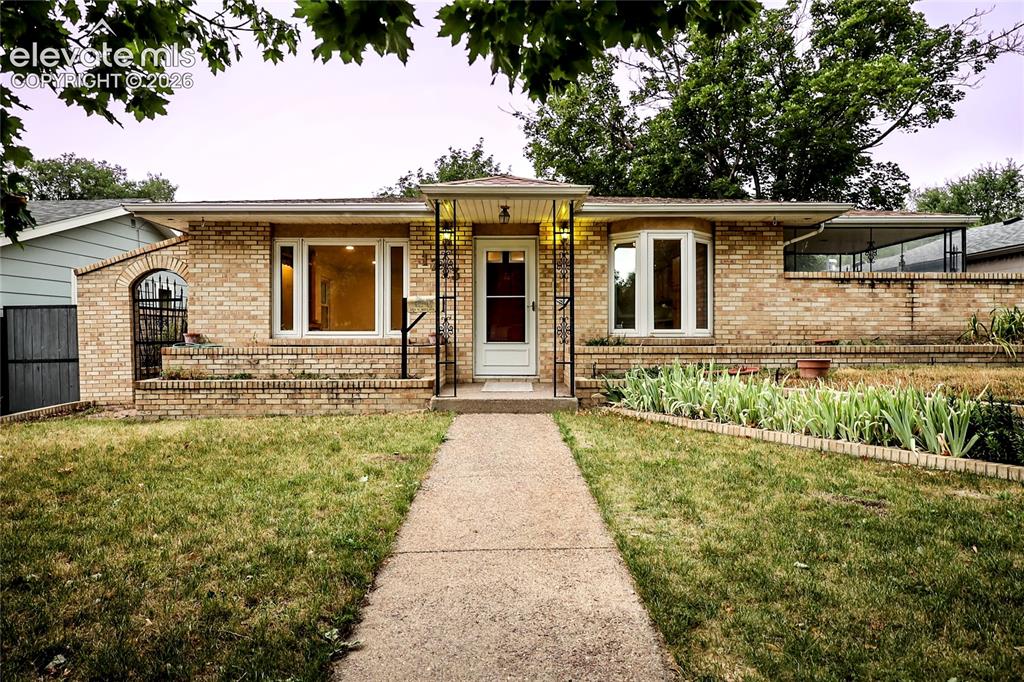 Caption: Brick exterior with a covered entry, established landscaping, and an arched brick detail
