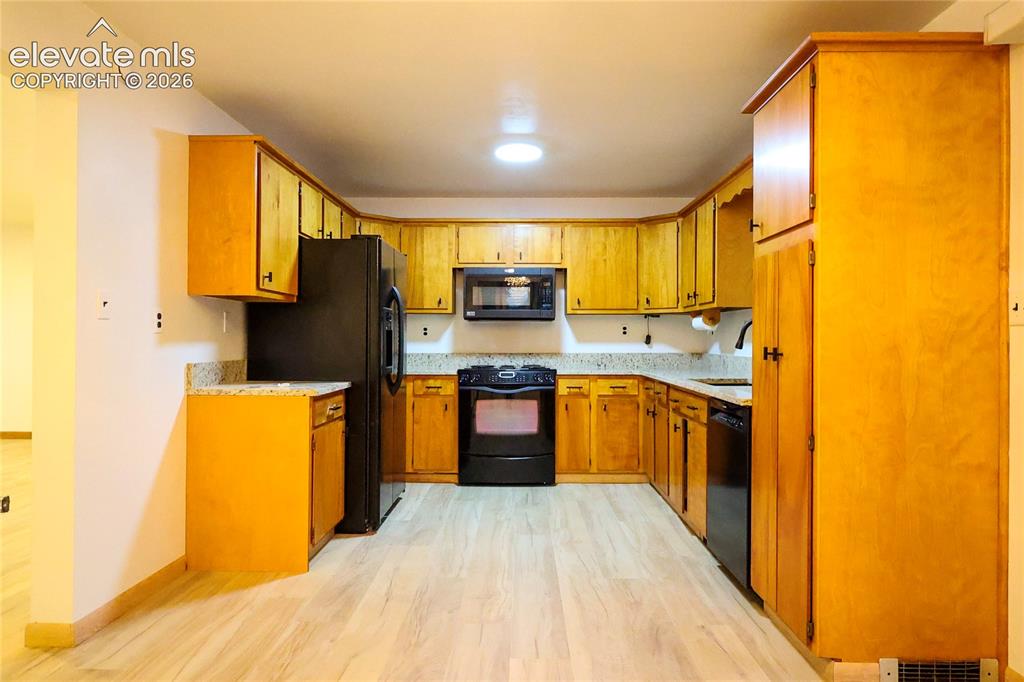 Image 13 of 40: U-shaped kitchen with wood-finish cabinetry, light-toned countertops, and l