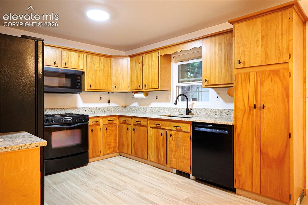 Image 15 of 40: Kitchen featuring wood-finish cabinetry, granite-style countertops, wood-fi