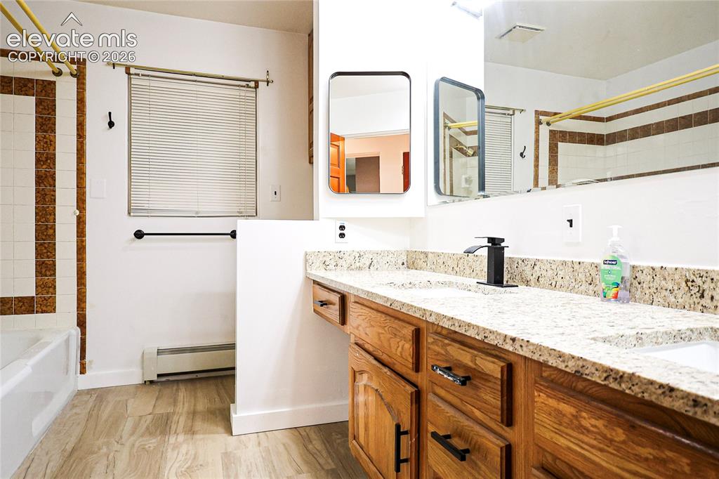 Image 19 of 40: Double vanity with granite-style countertop, wood-finish cabinetry, and und