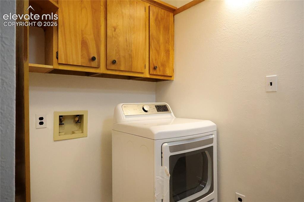 Image 22 of 40: Laundry area with wood cabinetry and an appliance hookup