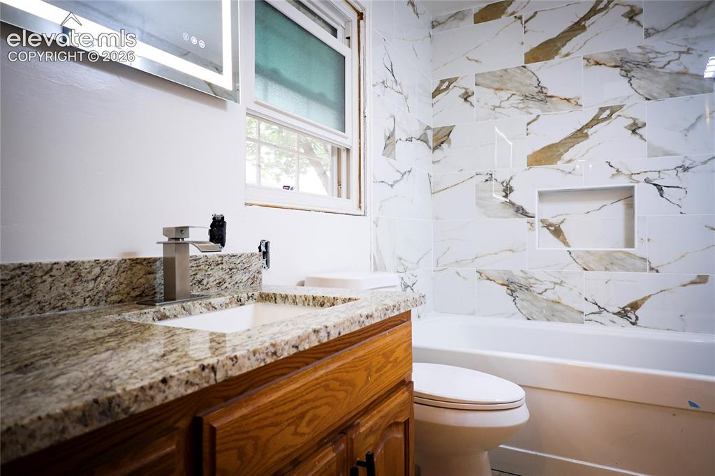 Image 26 of 40: Main bath Vanity with granite countertop and integrated sink, modern faucet