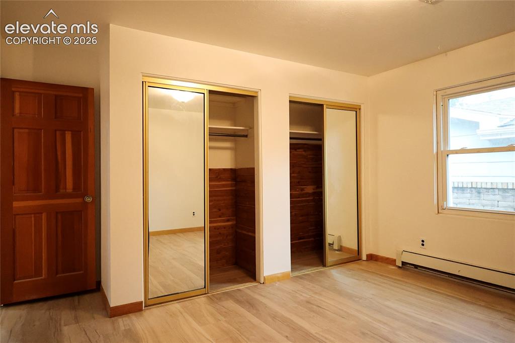 Image 29 of 40: Bedroom 3 Wood-finish flooring, two closets with mirrored sliding doors, an