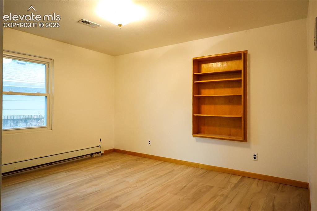 Image 30 of 40: Bedroom 3 Wood-finish flooring, built-in shelving, and a double-pane window