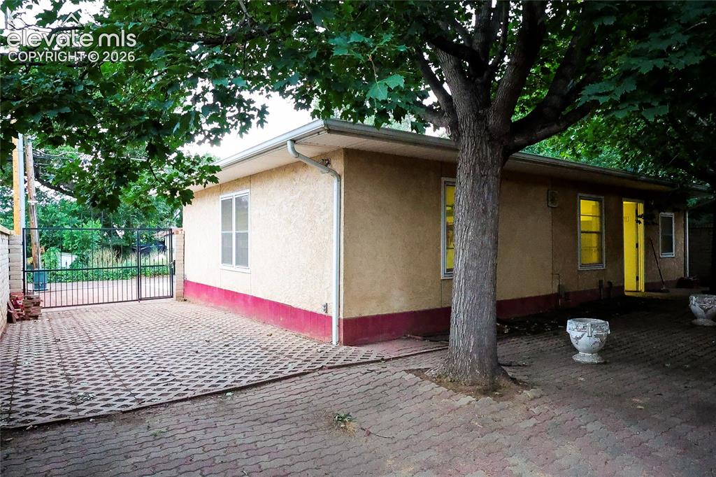 Image 6 of 40: Stucco exterior with a contrasting lower band, white gutters, multiple wind