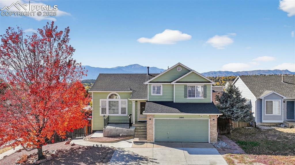 Caption: View of front of house with a shingled roof, a mountain view, brick siding, and concrete driveway