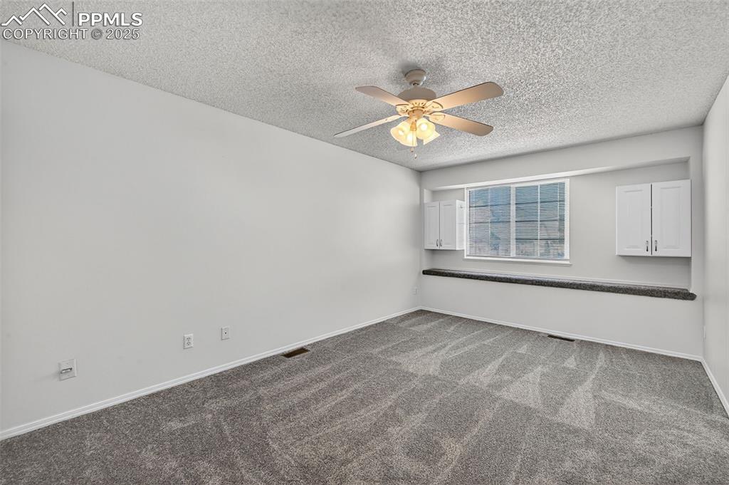 Image 17 of 30: Primary bedroom featuring a textured ceiling and a ceiling fan, extra stora