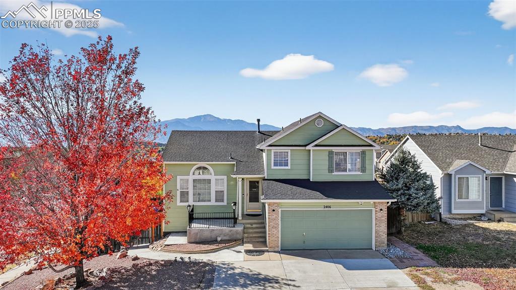Image 2 of 30: View of front of property with a mountain view, driveway, brick siding, and