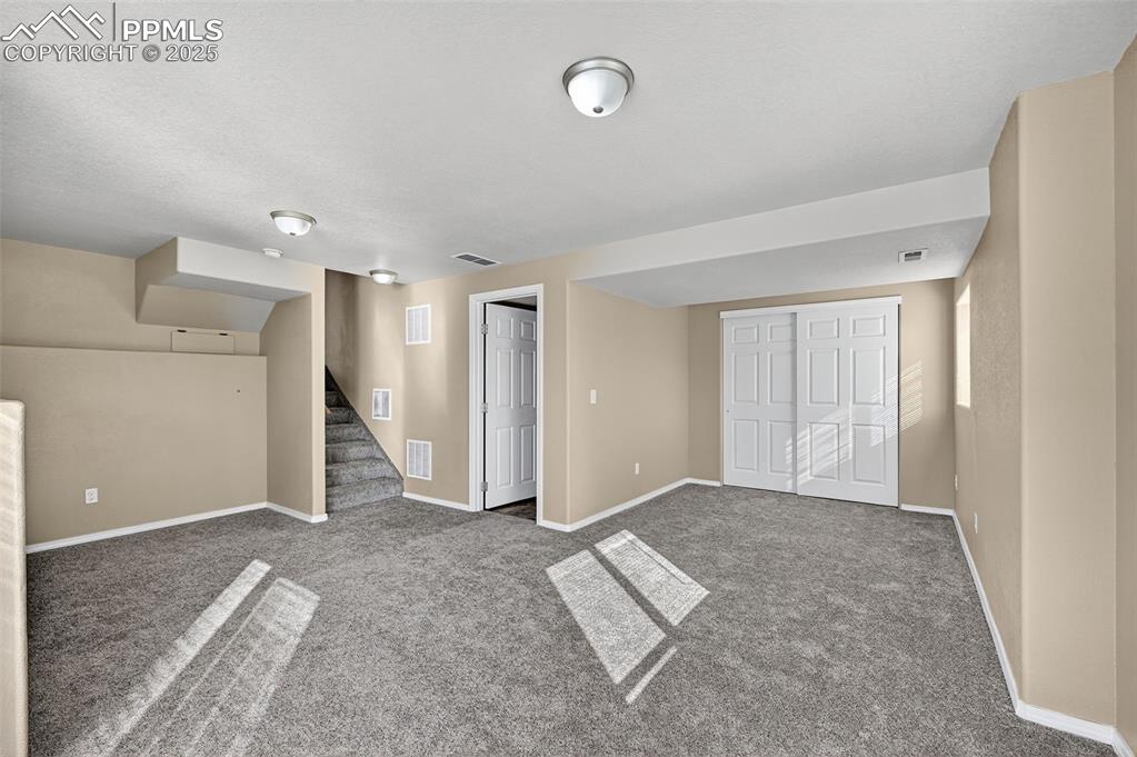Image 27 of 30: Finished basement featuring carpet flooring and stairs. and walkout.