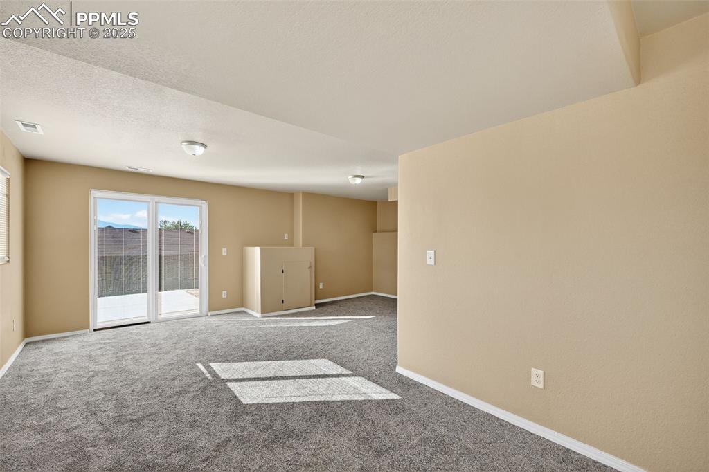 Image 28 of 30: Carpeted Guest room with baseboards and a textured ceiling and walkout slid