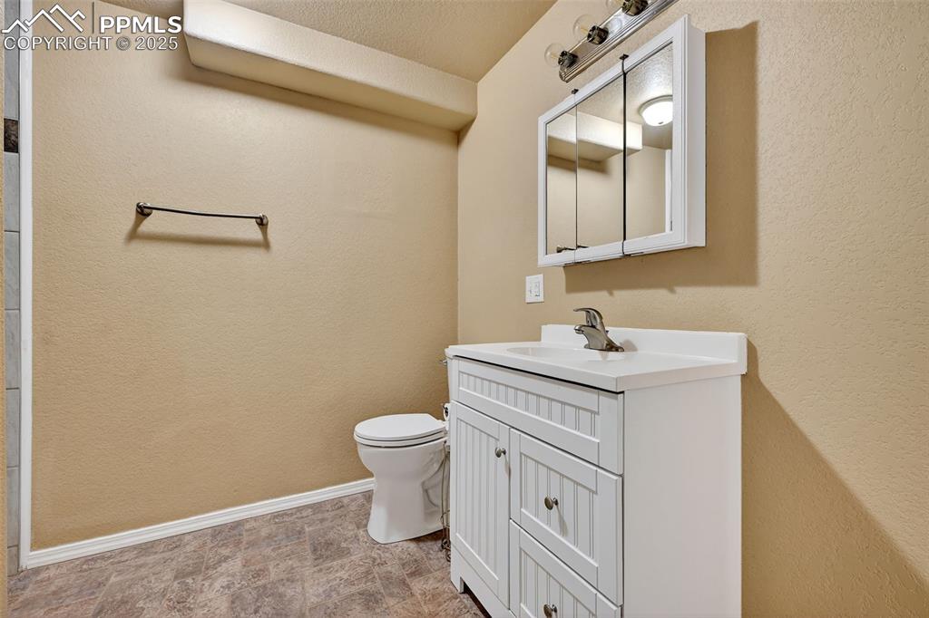 Image 29 of 30: Bathroom featuring a textured wall, vanity, and stone finish floors