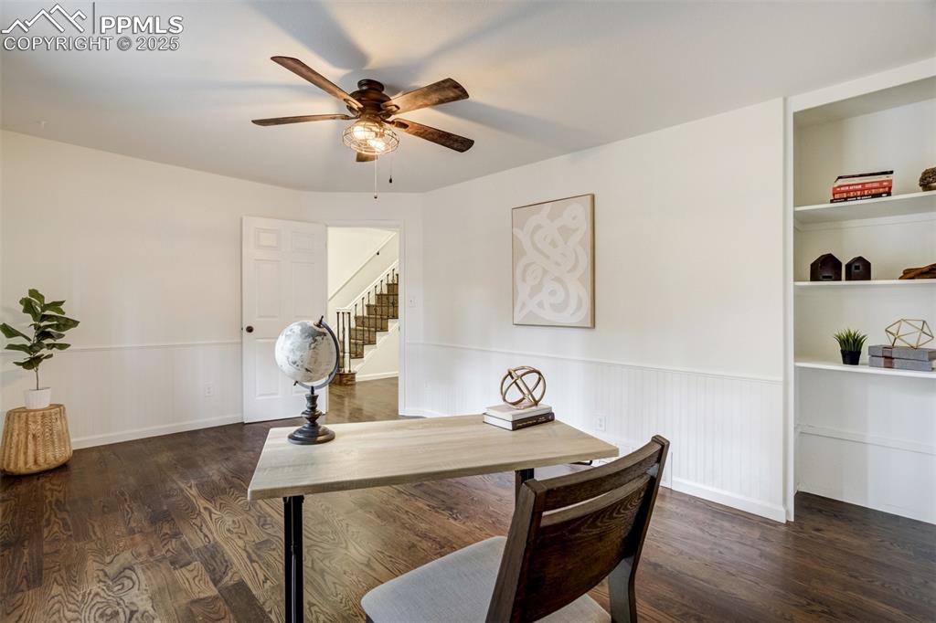 Image 17 of 50: Large office on main level with built in shelving and wainscoting