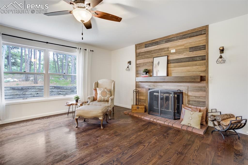 Image 8 of 50: Charming fireplace with wood accents and large picture window