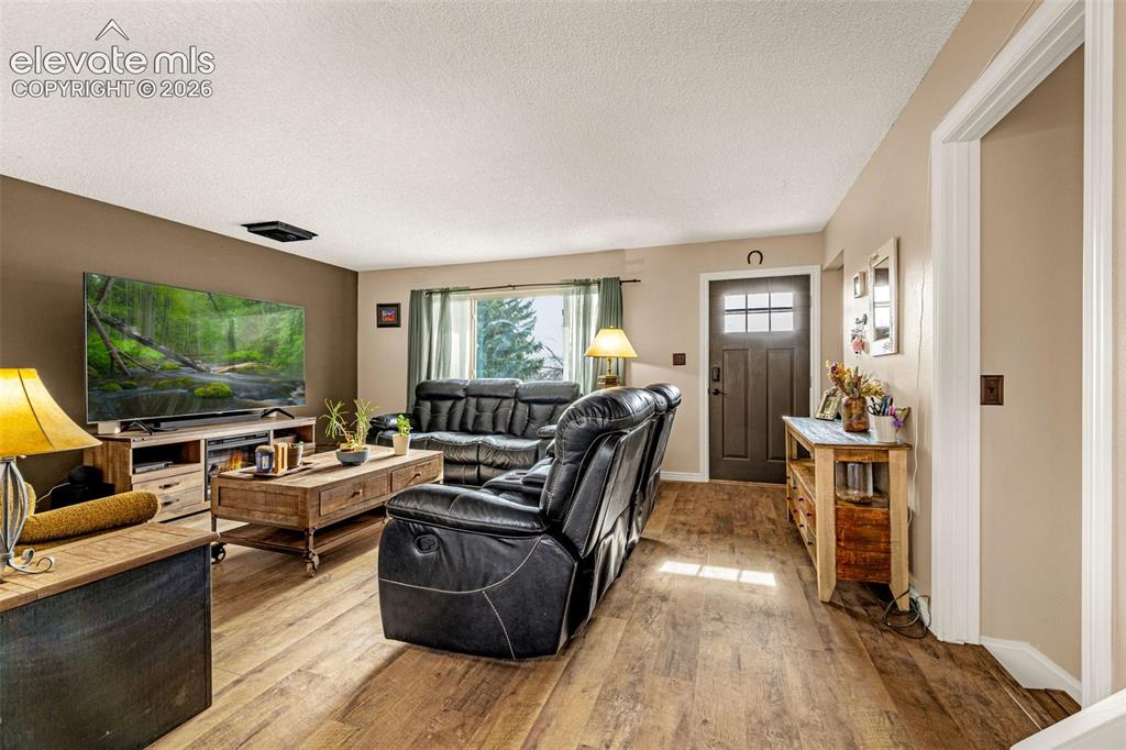 Image 10 of 30: Living area featuring wood-finish flooring, a dark-toned accent wall, and a