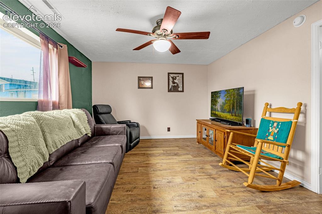 Image 11 of 30: Wood-finish flooring, ceiling fan with integrated lighting, and large windo