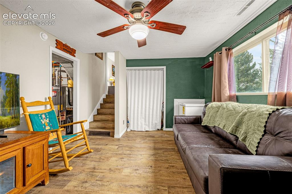 Image 12 of 30: Wood-finish flooring, ceiling fan with integrated lighting, accent wall, an