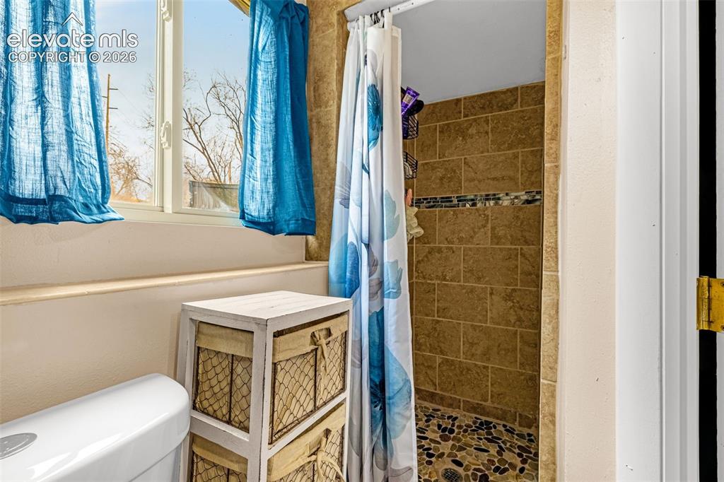 Image 16 of 30: Bathroom featuring a shower stall with stone-tile surround, river-rock floo