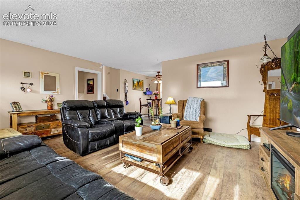 Image 4 of 30: Living area featuring wood-finish flooring, ceiling with textured finish, a