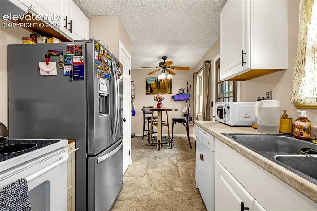 Image 9 of 30: Kitchen featuring white cabinetry with matte black hardware, stainless stee