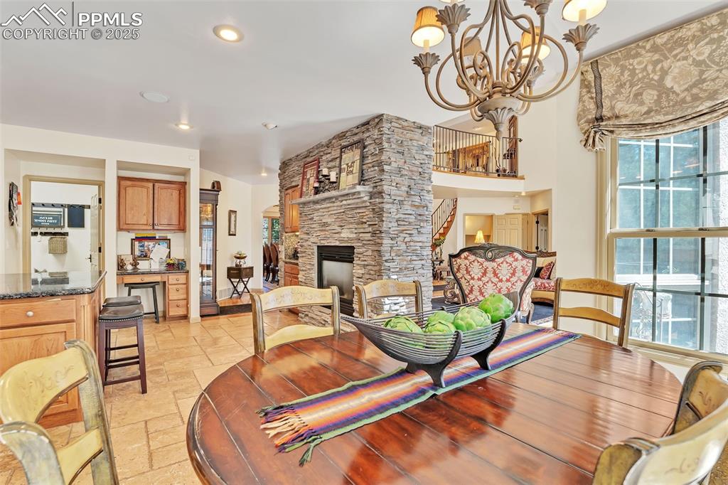 Image 10 of 45: Dining room with stone tile floors, a fireplace, a notable chandelier, and 