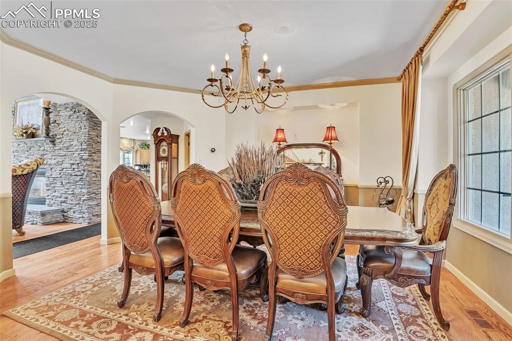 Image 12 of 45: Dining area featuring wood finished floors, visible vents, ornamental moldi