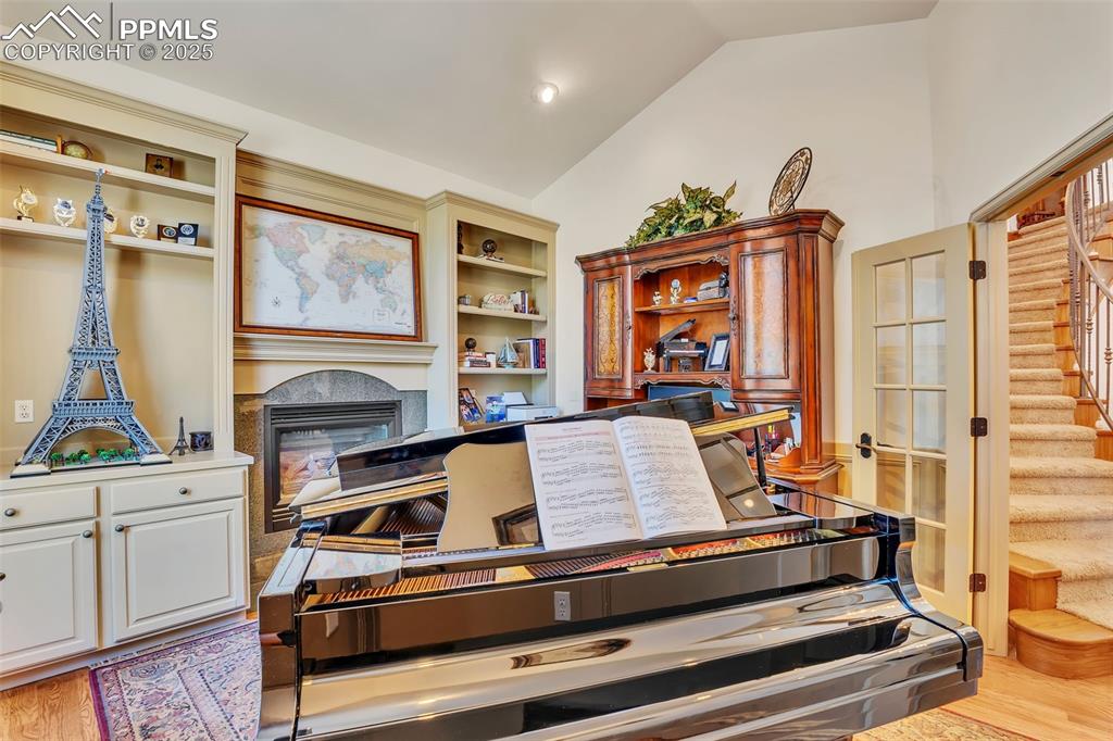 Image 13 of 45: Office with light wood-style floors, a glass covered fireplace, and high va