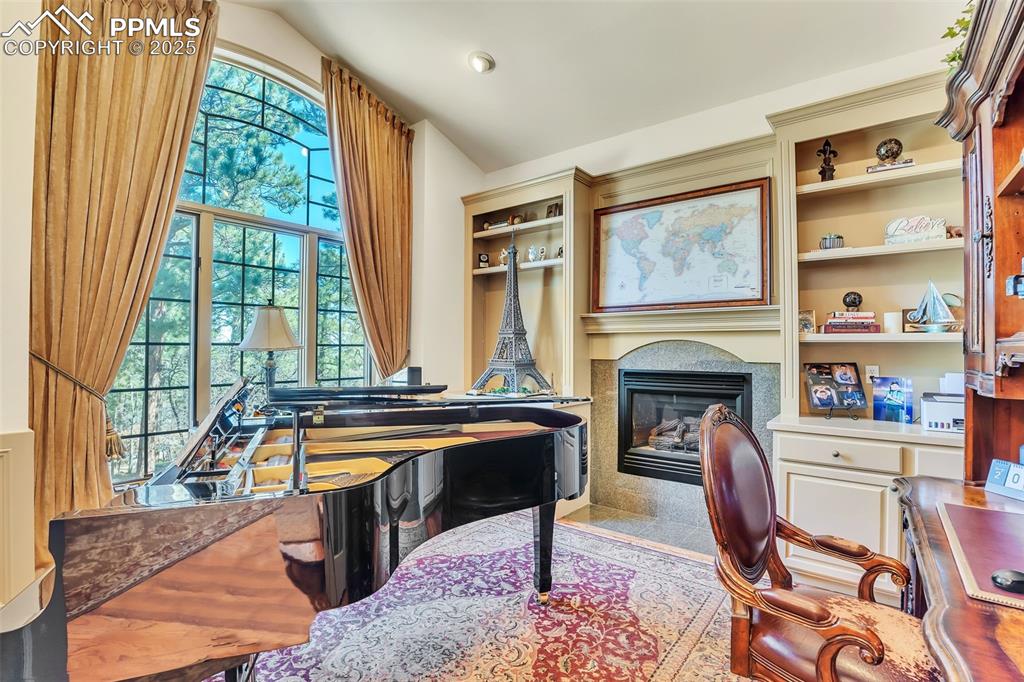 Image 14 of 45: Sitting room featuring a fireplace with flush hearth, vaulted ceiling, and 