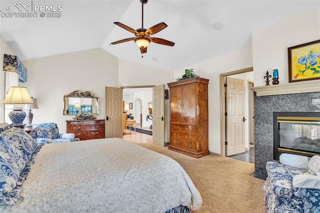 Image 16 of 45: Bedroom with carpet, ceiling fan, arched walkways, a fireplace, and baseboa