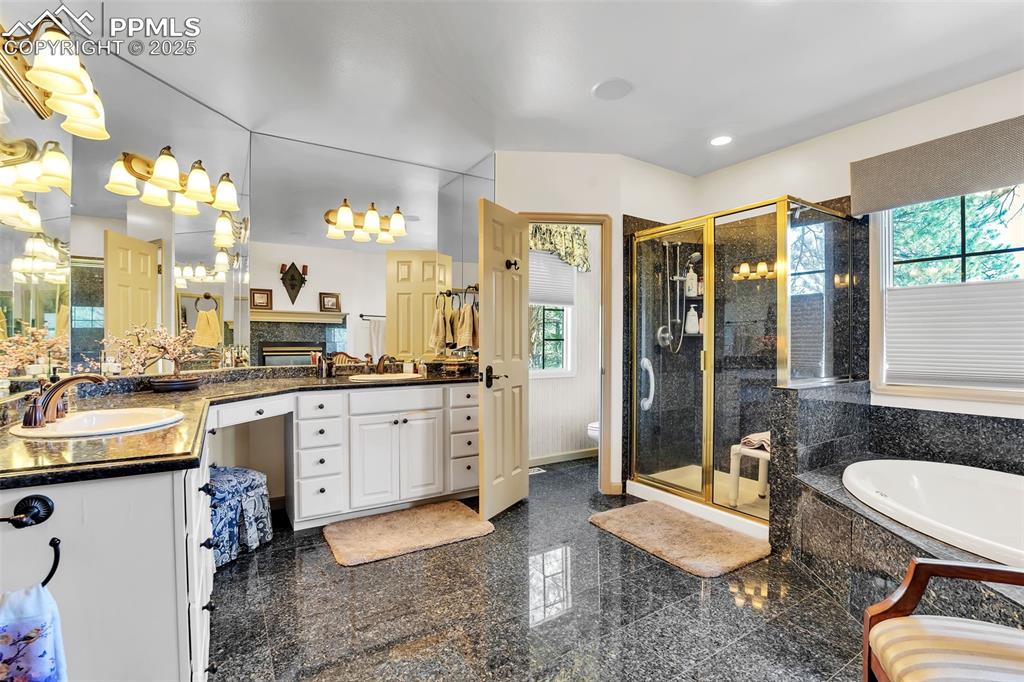 Image 18 of 45: Bathroom with a bath, a stall shower, vanity, and plenty of natural light