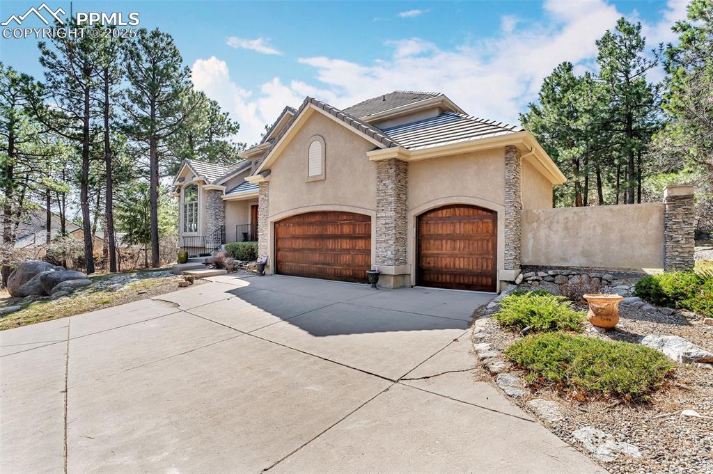 Image 2 of 45: View of front of house featuring a tiled roof, stone siding, concrete drive