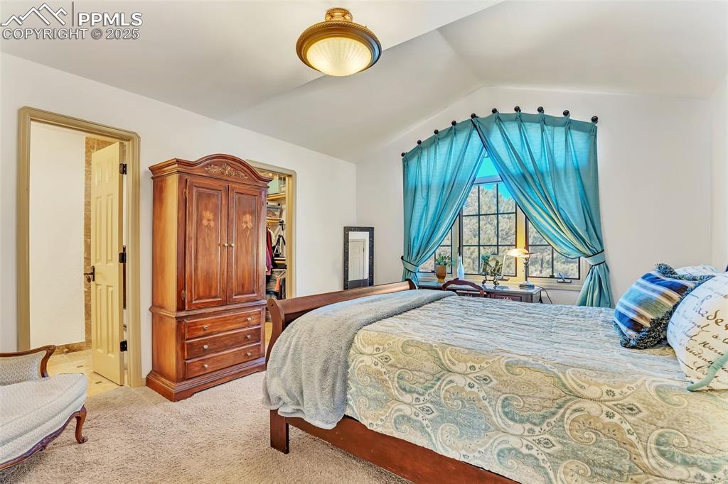 Image 21 of 45: Bedroom featuring lofted ceiling, light carpet, and a walk in closet