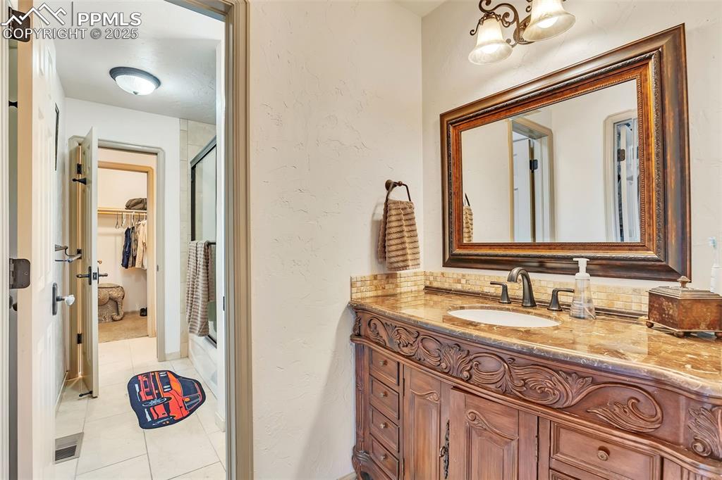 Image 26 of 45: Full bath featuring a shower stall, a spacious closet, tile patterned floor