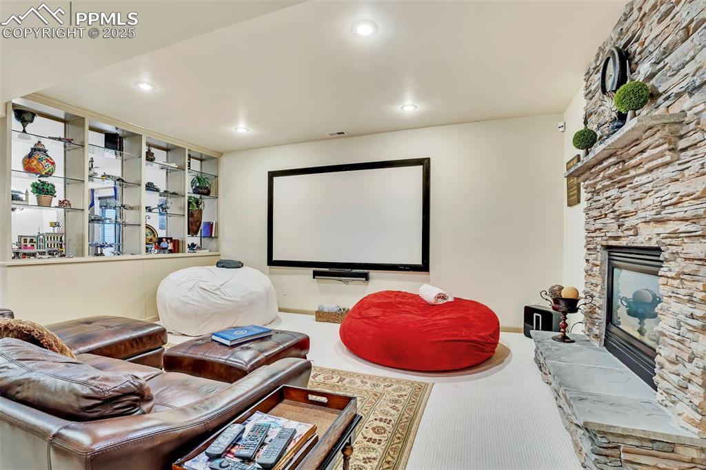 Image 29 of 45: Carpeted cinema room with a stone fireplace and recessed lighting
