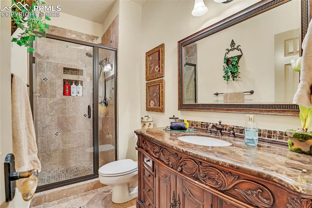 Image 35 of 45: Bathroom featuring vanity, toilet, and a stall shower