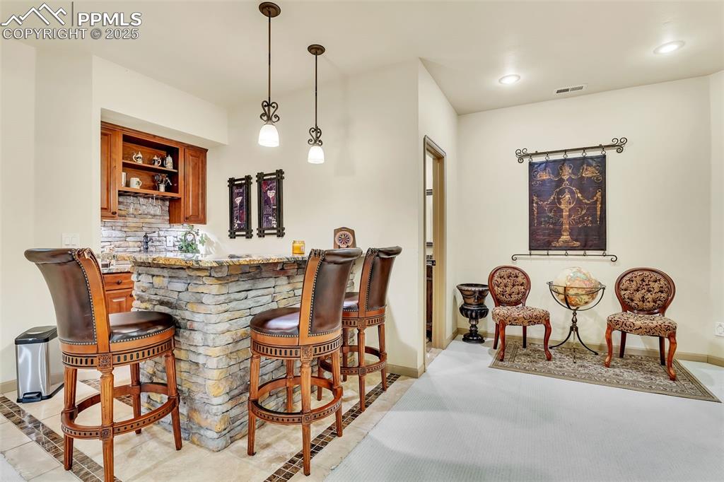 Image 36 of 45: Bar with indoor bar, baseboards, and light tile patterned flooring