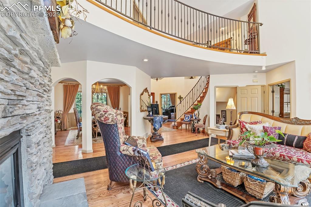 Image 5 of 45: Living room with arched walkways, a towering ceiling, wood finished floors,
