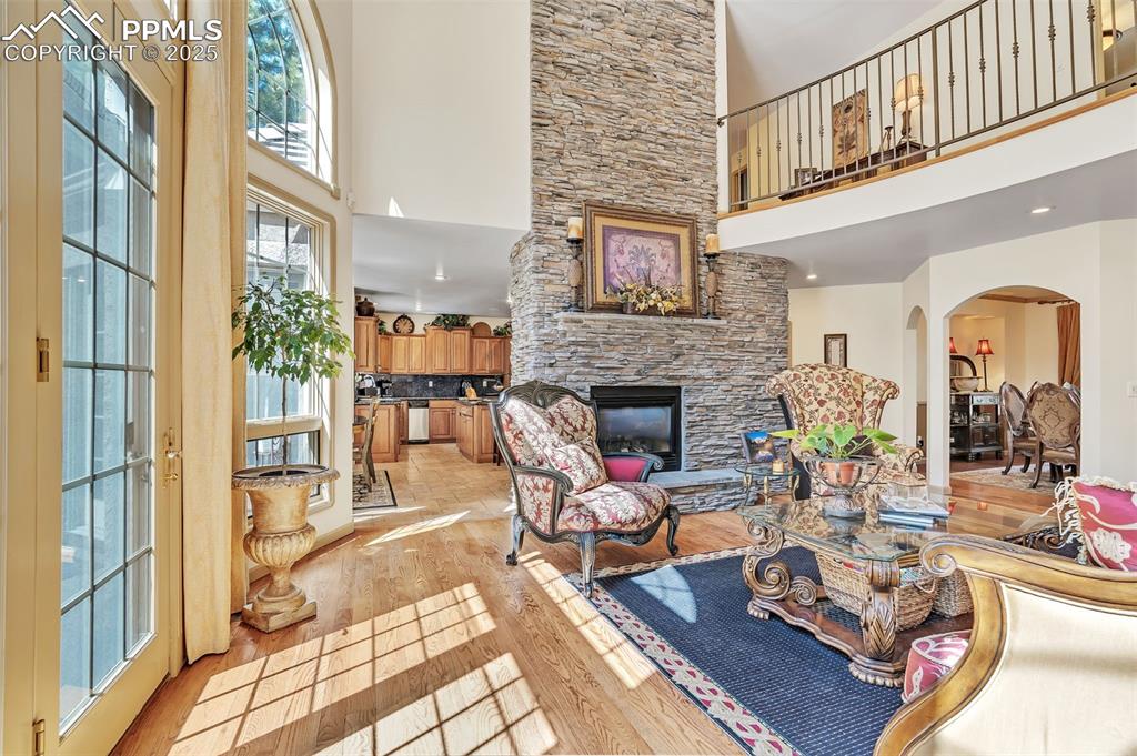Image 6 of 45: Living room with a stone fireplace, a towering ceiling, arched walkways, an